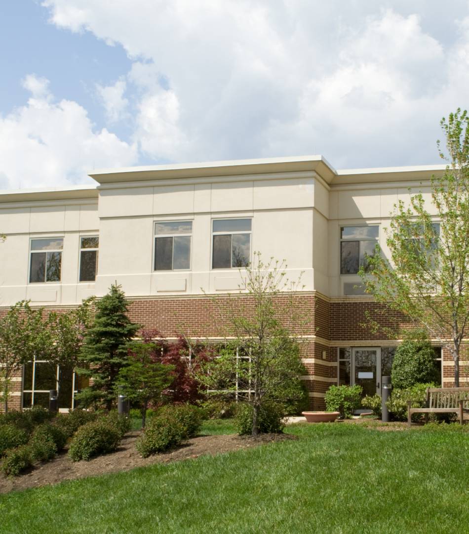 Modern two-story building with large windows and landscaped greenery.