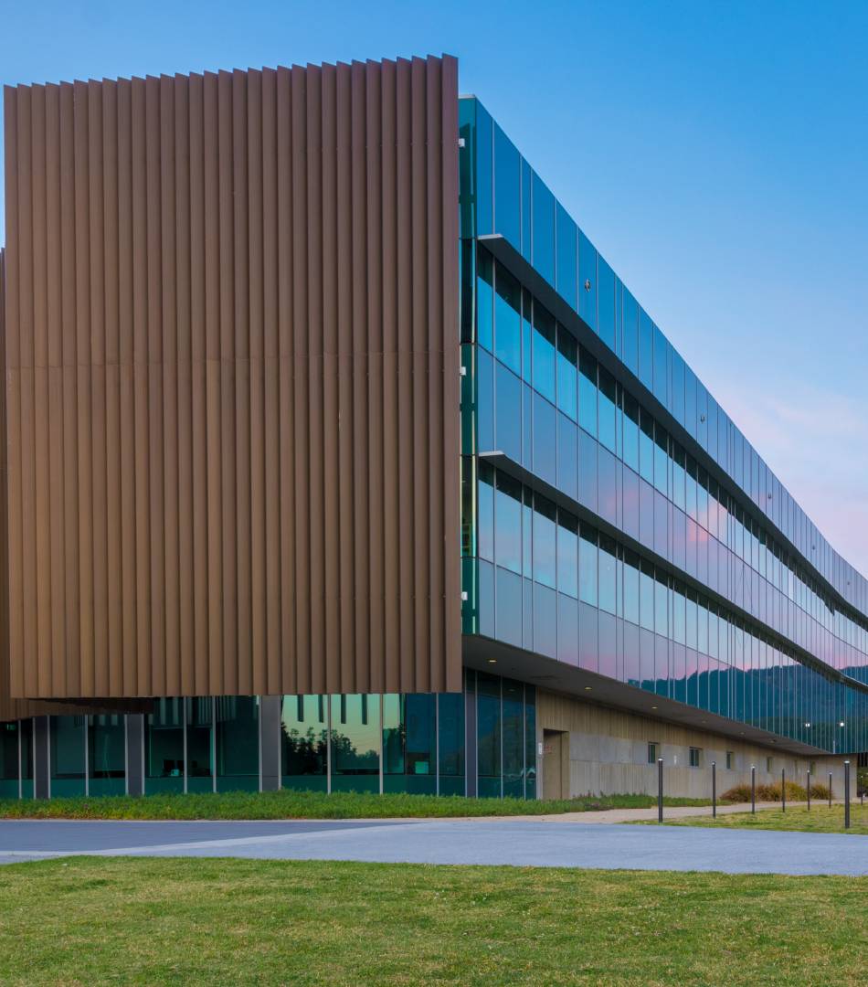 Modern building with glass and wood paneling under a clear blue sky.