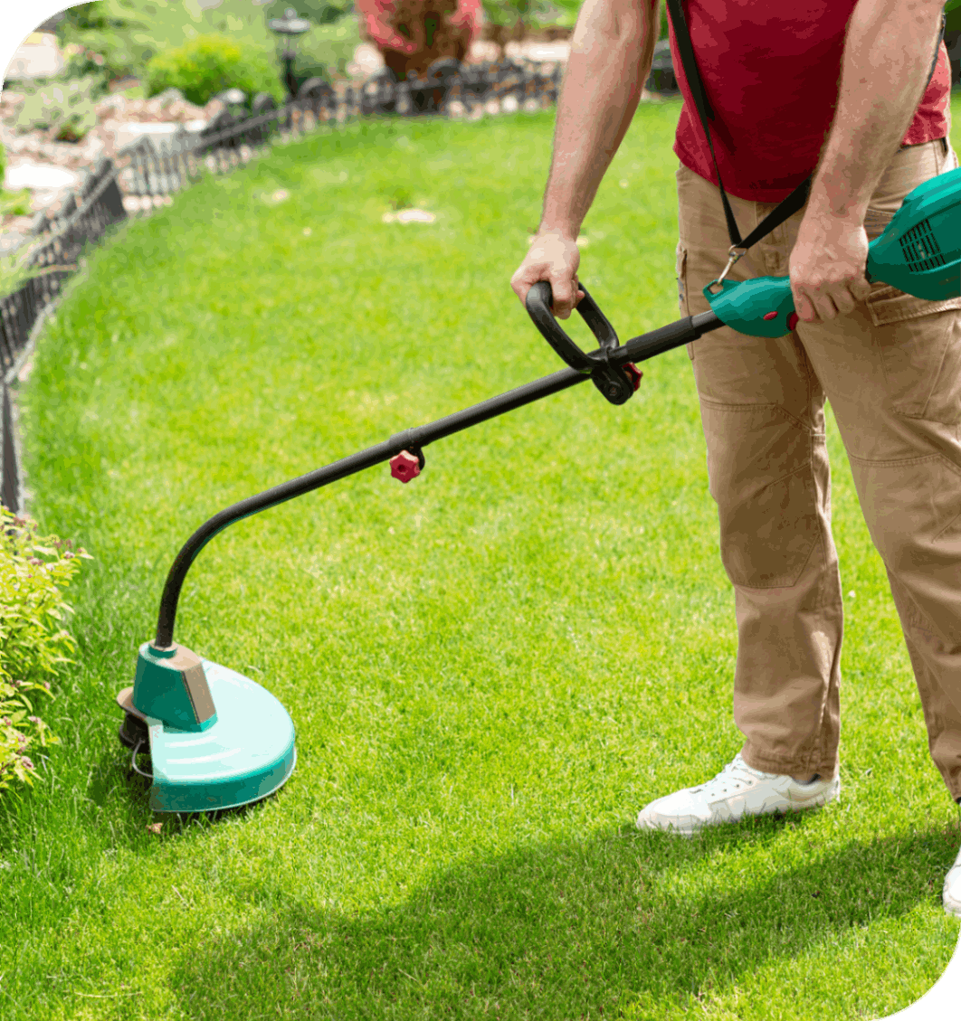 Man trimming grass with electric lawn trimmer.